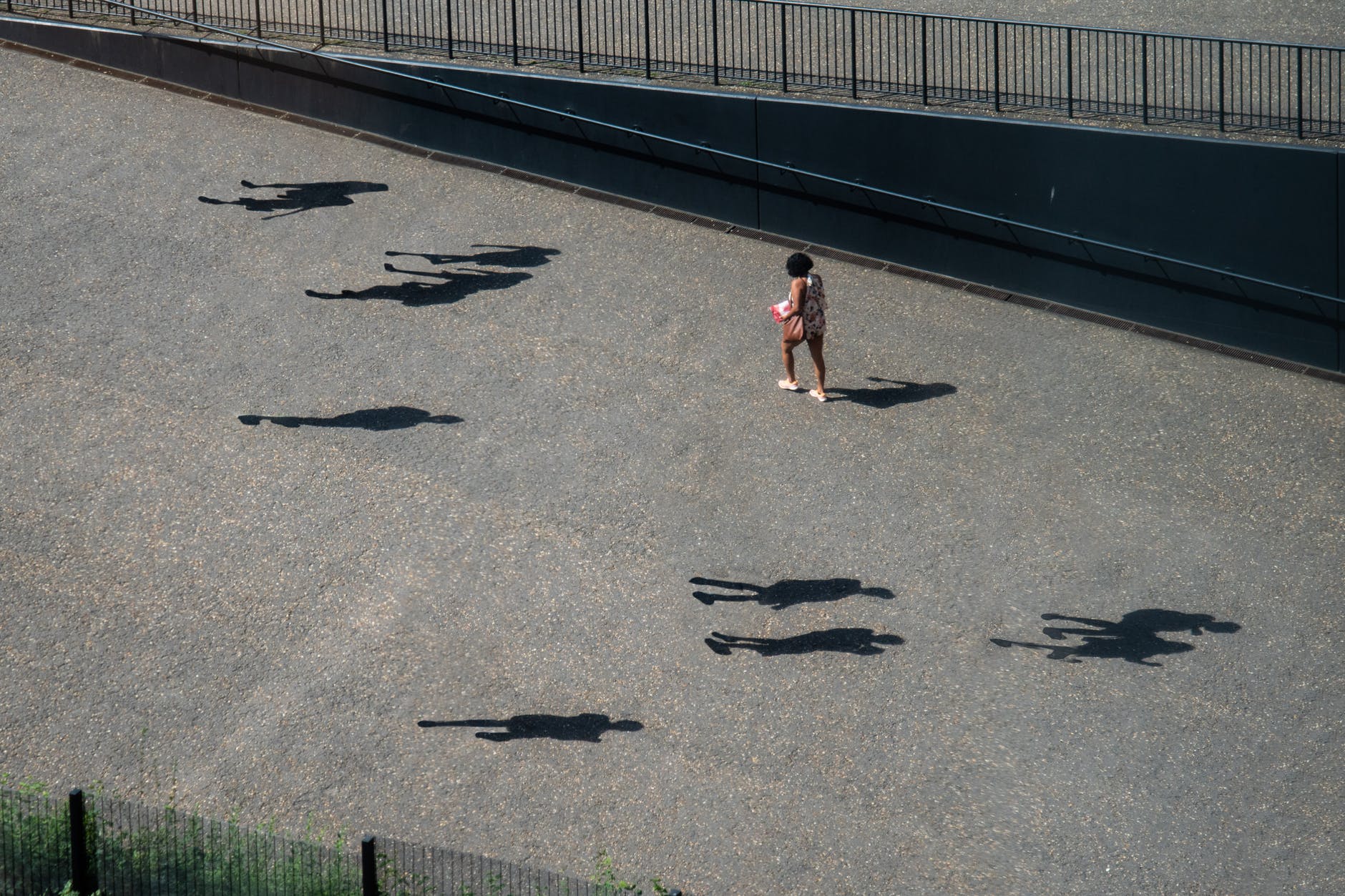 girl in pink shirt and black pants walking on gray concrete pathway